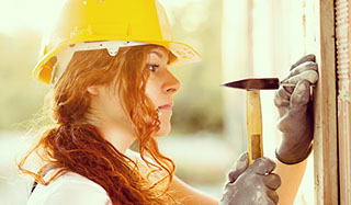 White woman builder hammering in a nail