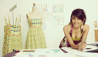 Indian woman fashion designer leaning over table with patterns and drawings