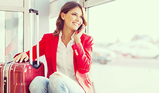 Single white woman traveller sitting with suitcase talking on the phone